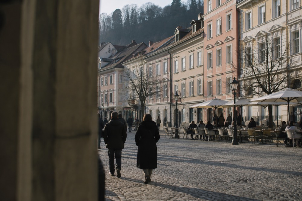 Cobbled square in Ljubljana old town with pastel coloured buildings and outdoor tables