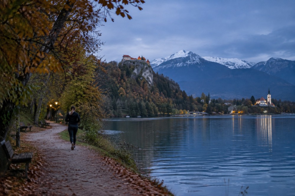 The walking path along Lake Bled in autumn with the castle on the cliff above