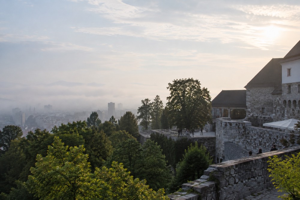 Morning fog resting over the Ljubljana skyline with castle hill emerging above the mist