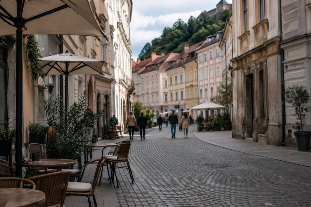 Cobbled street in the pedestrianised centre of Ljubljana lined with cafe tables and baroque facades