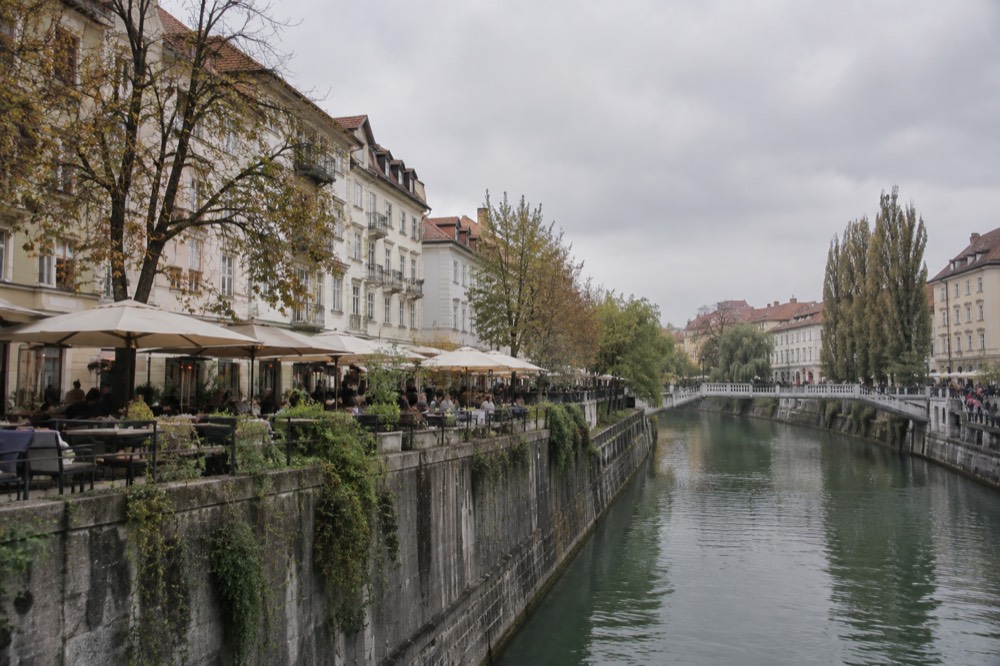 A row of restaurant terraces beside the Ljubljanica river in Ljubljana