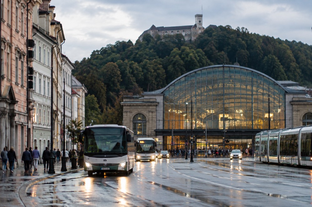 The glazed facade of Ljubljana train station with buses and trams passing on the street outside