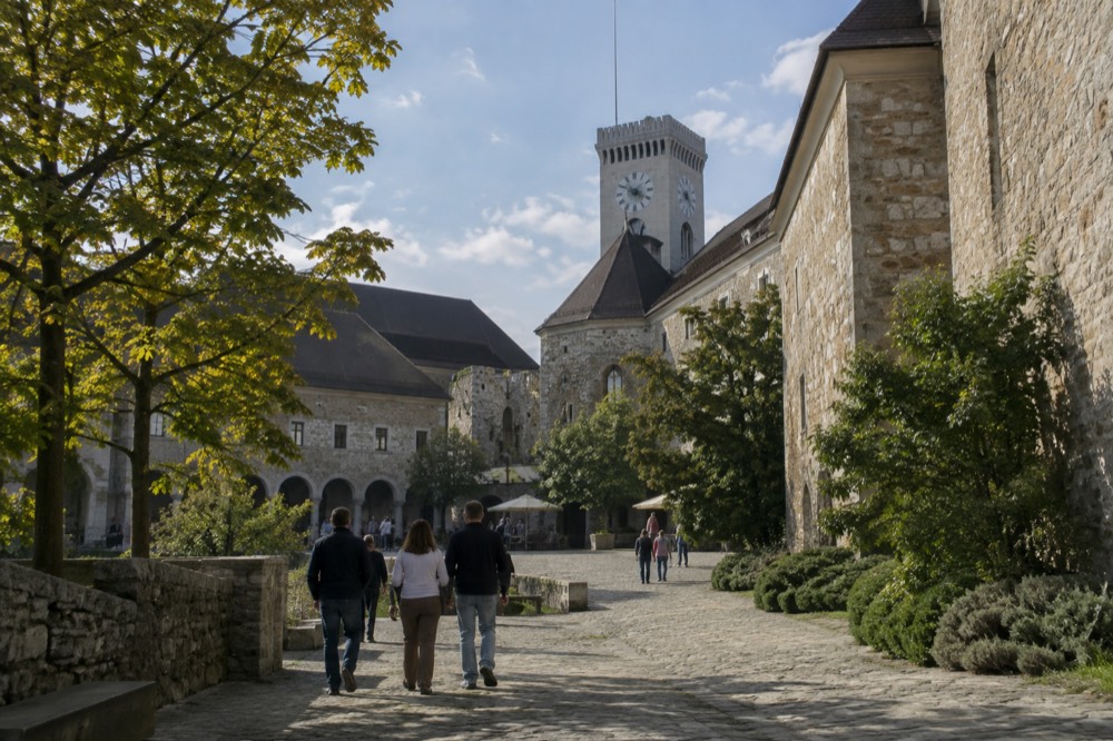 The stone courtyard of Ljubljana Castle with the clock tower rising above the walls