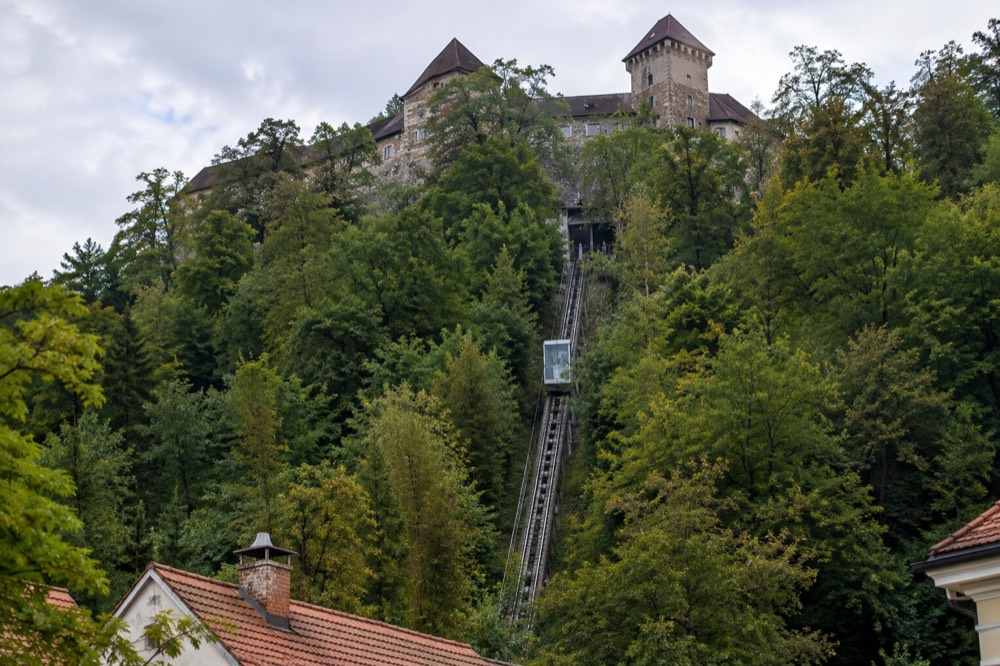 A funicular carriage climbing the steep rail towards Ljubljana Castle above the tree line