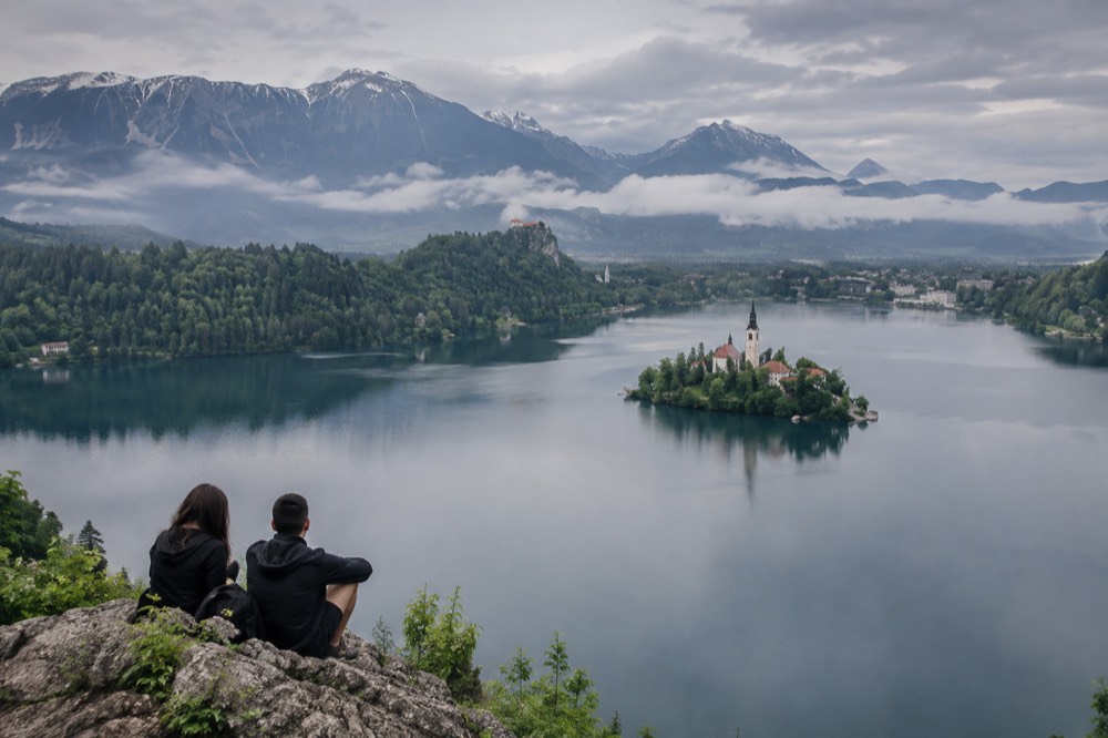 Calm morning water at Lake Bled with mist over the far shore and mountains