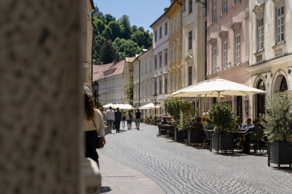 Pedestrian street in Ljubljana old town with pastel buildings and cafe tables
