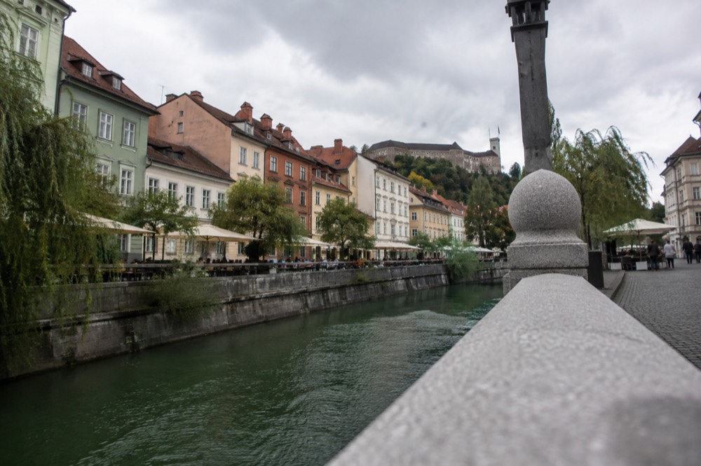 Pastel coloured buildings and café tables along the Ljubljanica river in the pedestrianised centre of Ljubljana