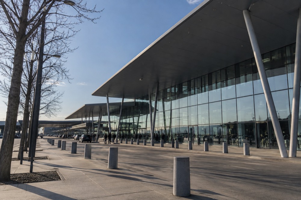 A small modern airport terminal building with glass walls under a blue sky