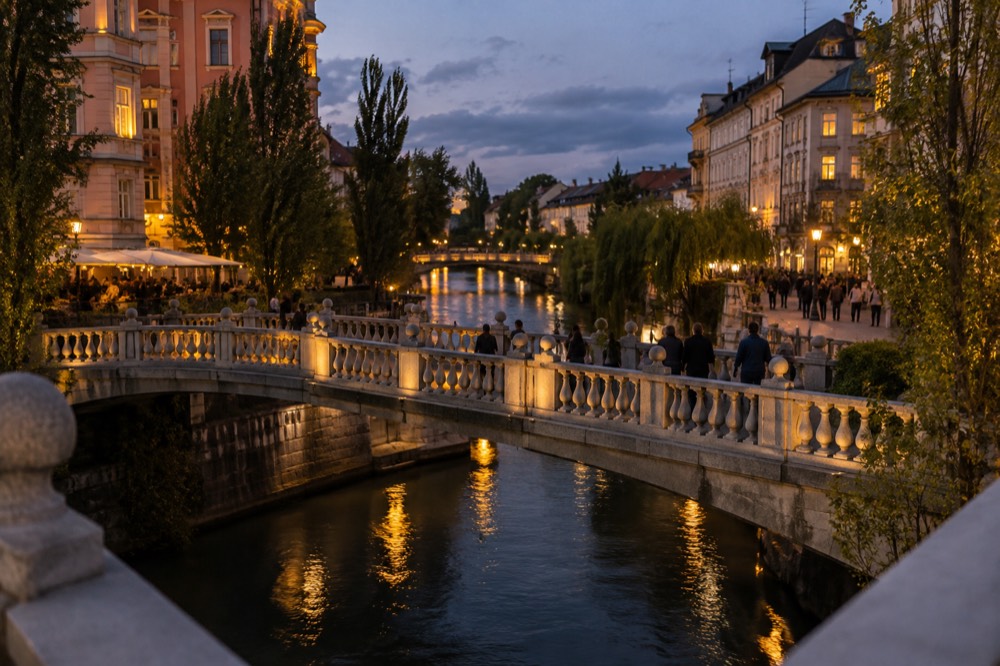 The Triple Bridge and the Ljubljanica river in Ljubljana at dusk, with the lit facades of the Old Town along the bank