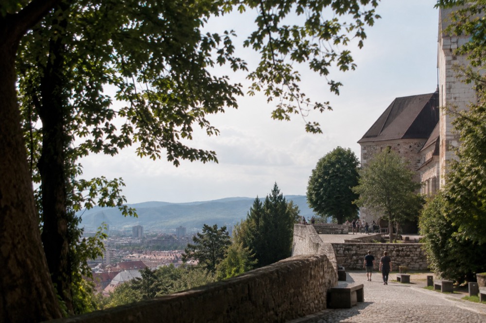 Ljubljana Castle walls and tower seen from the wooded hillside above the city rooftops