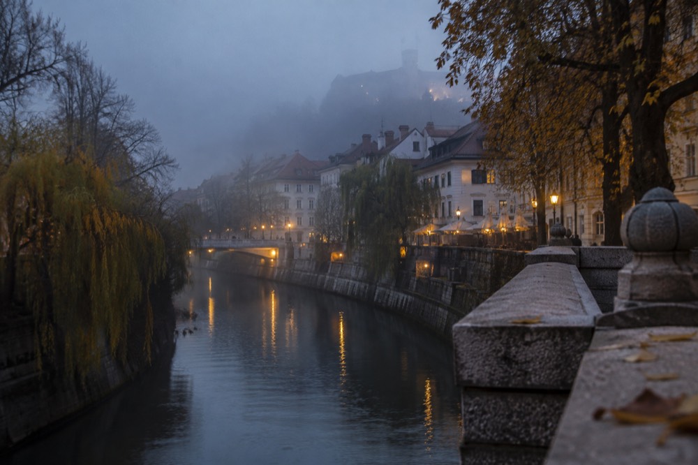 Fog over the Ljubljanica river and city rooftops in autumn