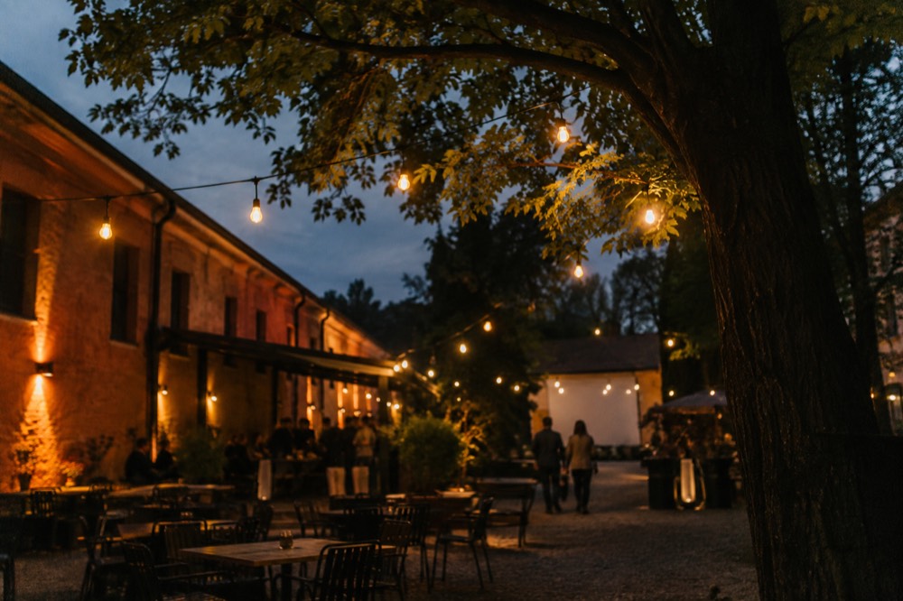 Painted barracks walls and string lights in a courtyard cultural venue at dusk