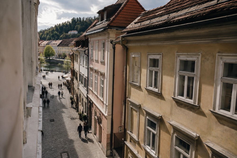 Narrow stone street in a small Slovenian old town opening onto a riverside square