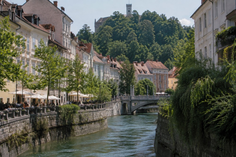 A clear stream flowing over limestone rocks in a green alpine valley