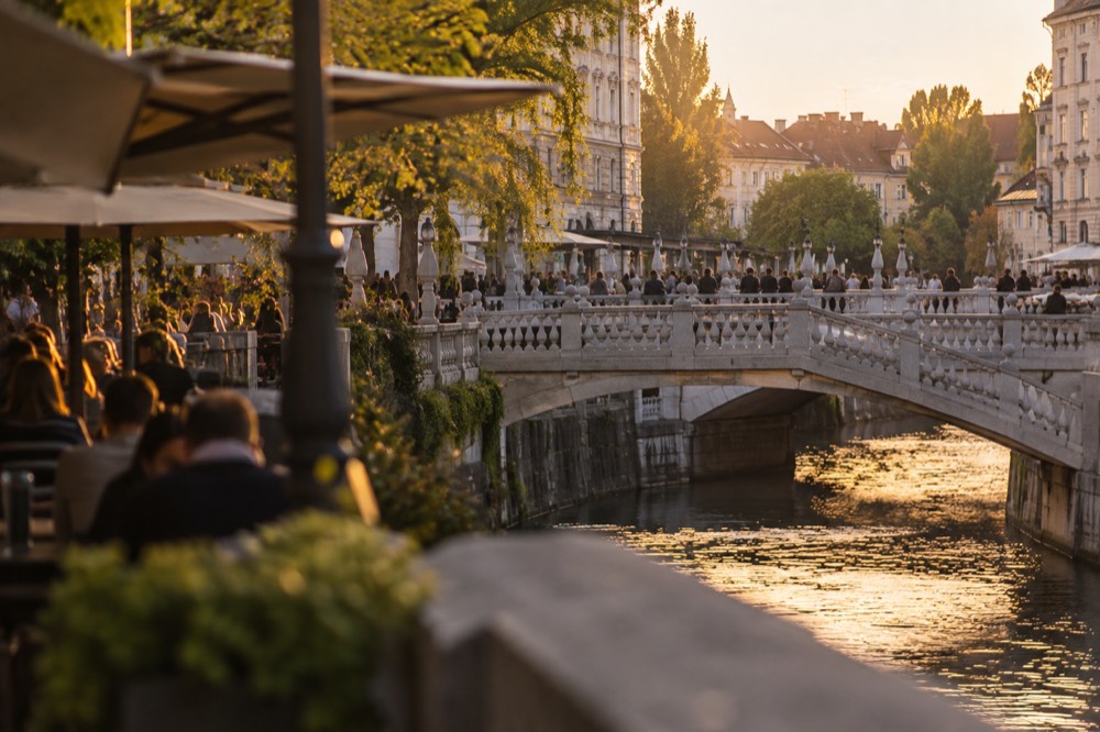 Cafes and passersby along the Ljubljanica river embankment near the Triple Bridge