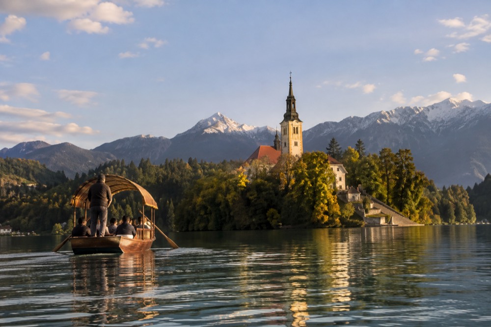 Wooden pletna boat approaching the church on Bled island