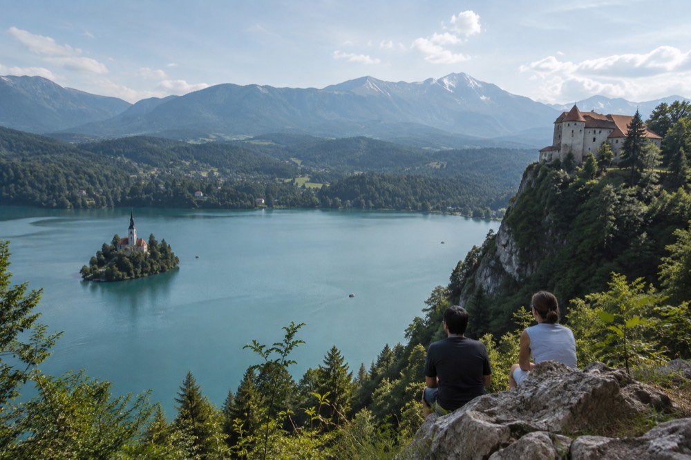 Bled Castle on its cliff above the lake with forested hills behind