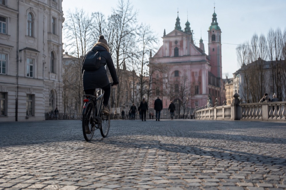 A cyclist crossing a car-free cobbled square in central Ljubljana
