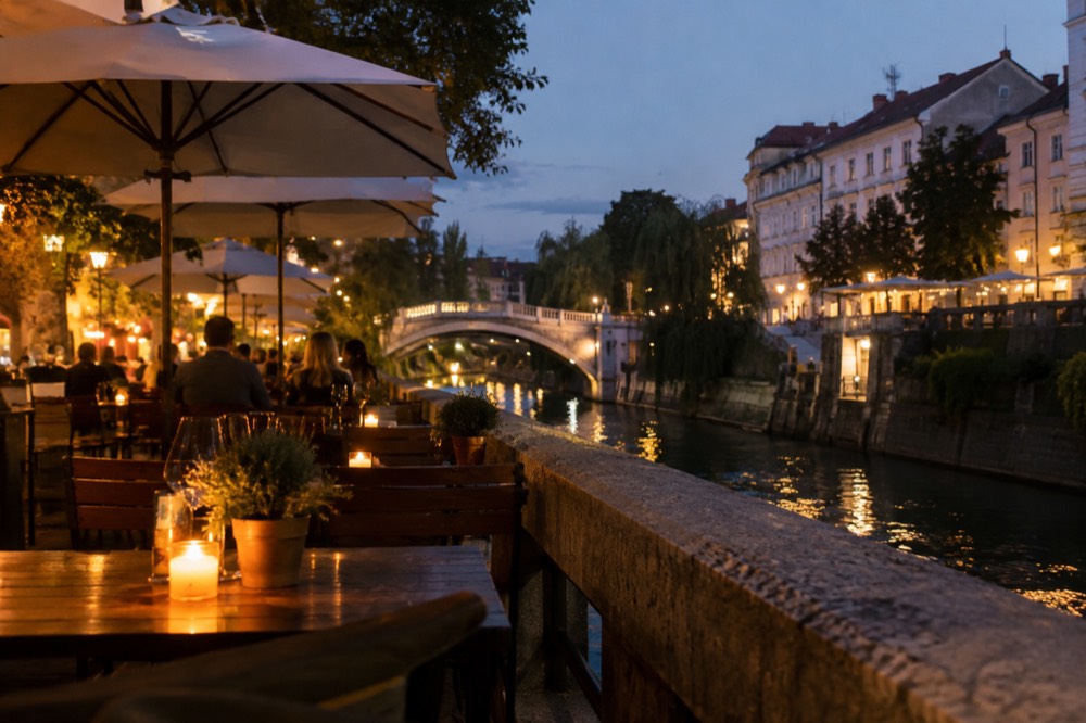 Outdoor restaurant tables beside the Ljubljanica river in the evening
