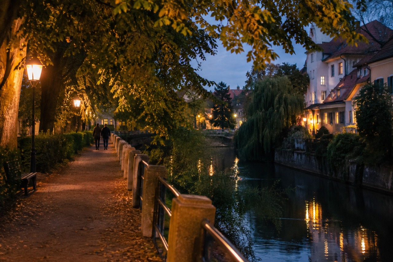 Quiet leafy street in Trnovo with trees overhanging a riverside walkway in soft evening light