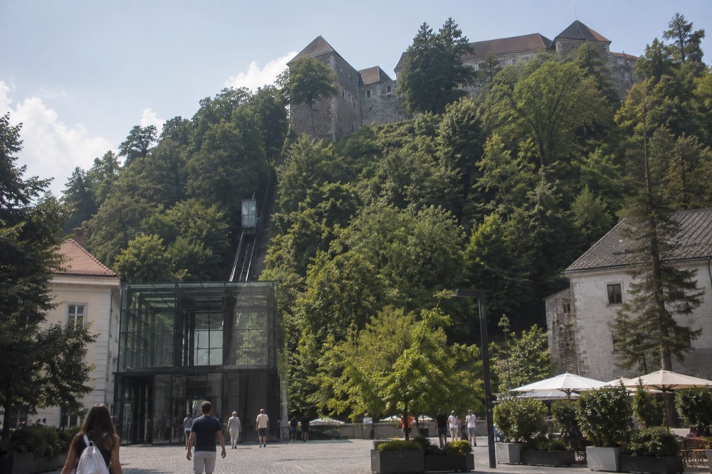 The glass-walled funicular cabin at the lower station on Krekov trg, with the castle hill rising behind it