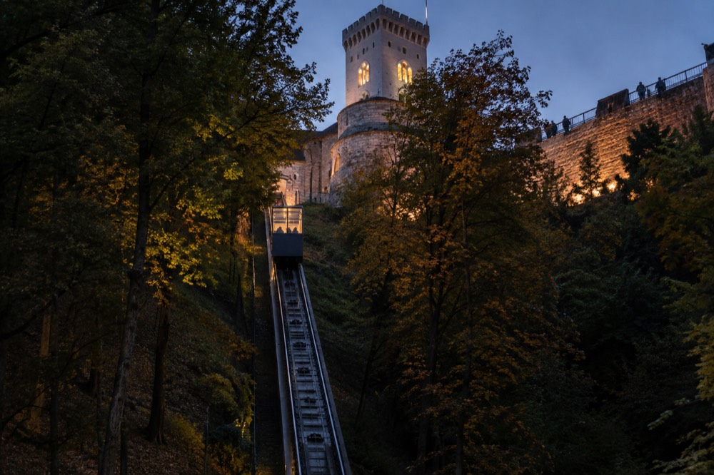 The castle courtyard in warm evening light, with visitors walking the rampart walkway beneath the Viewing Tower