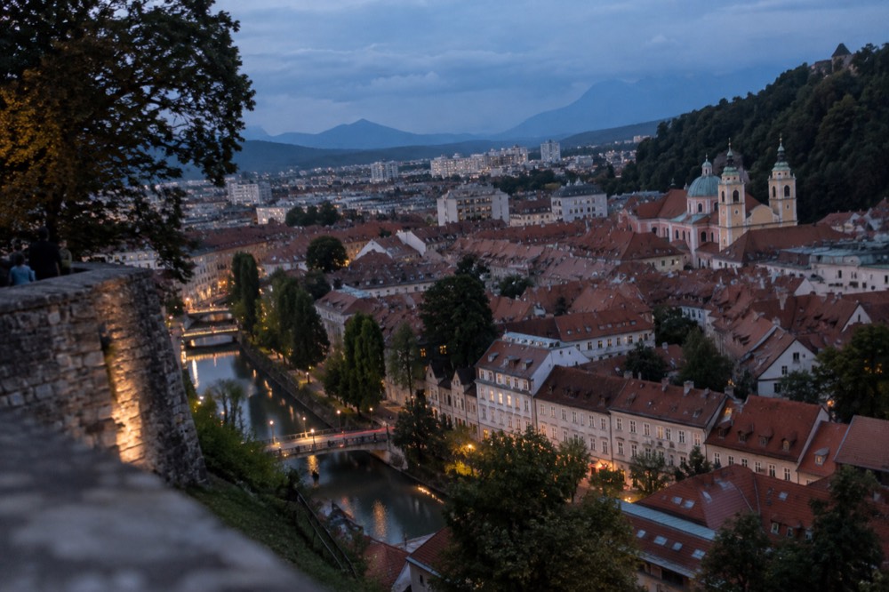 The view from the castle ramparts over the orange rooftops and church towers of Ljubljana's old town at dusk
