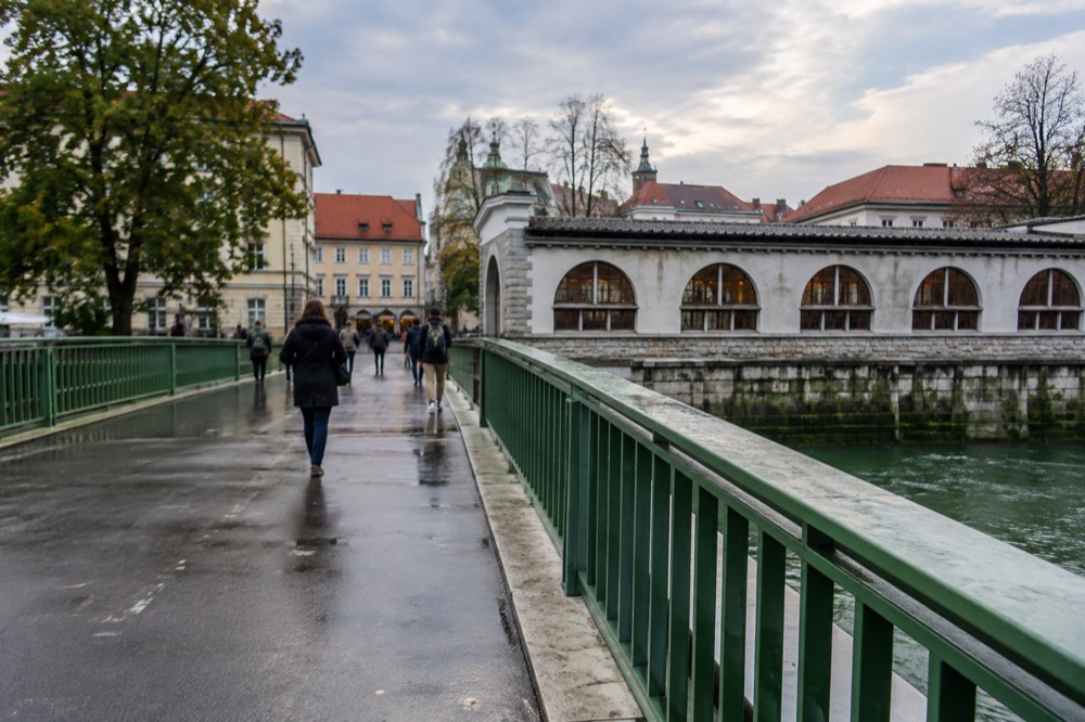 Pedestrian street leading toward a bridge with dragon statues, with market buildings behind