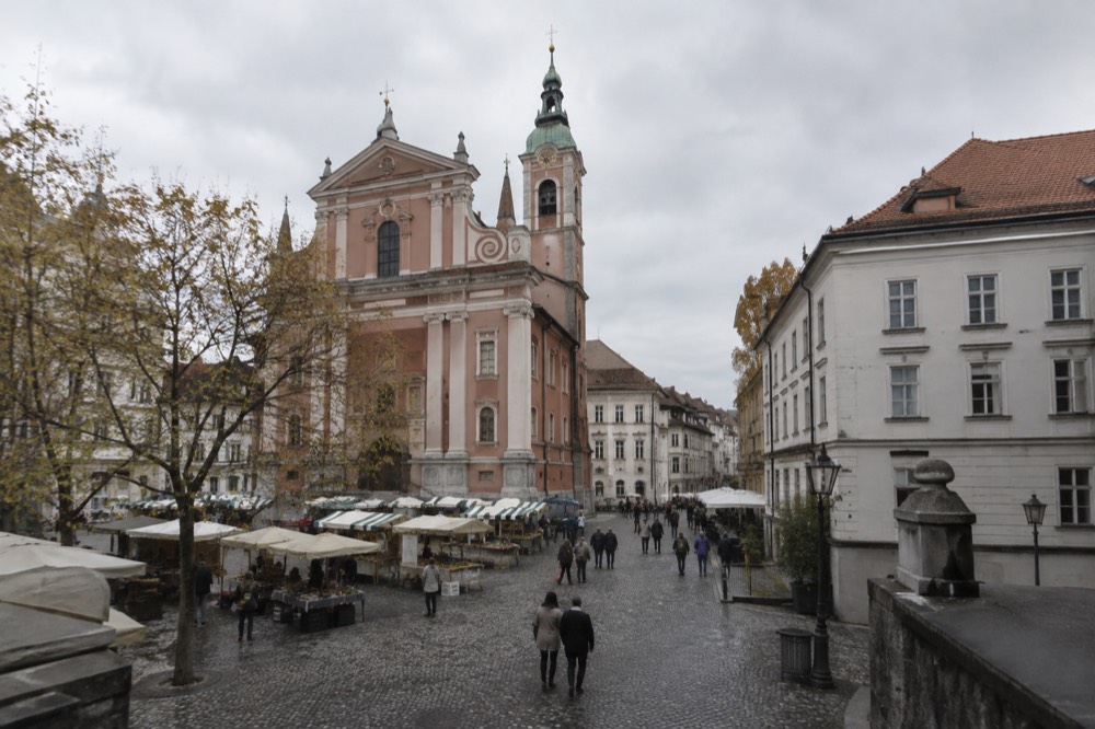 An old square with market awnings and a church tower rising above the stalls