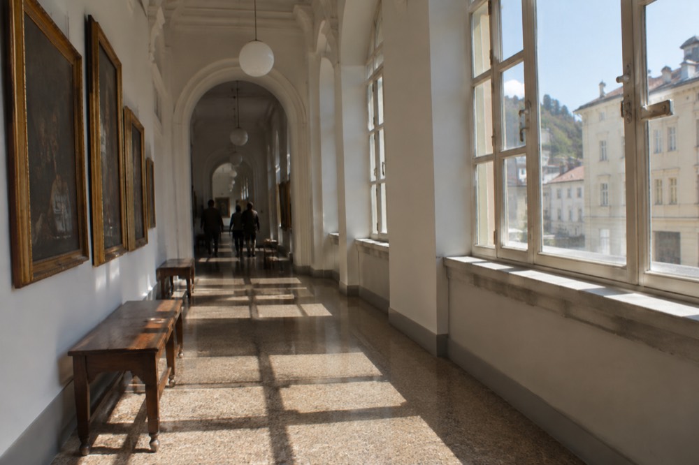 Museum corridor with wooden benches and framed paintings under soft lighting