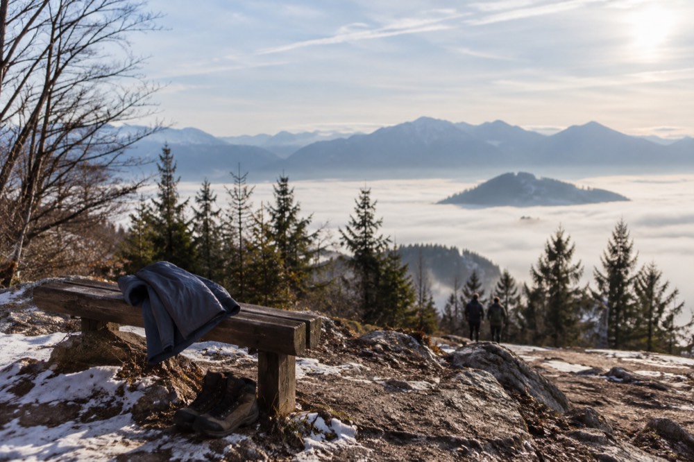 A pair of walking boots and a folded rain jacket on a wooden bench