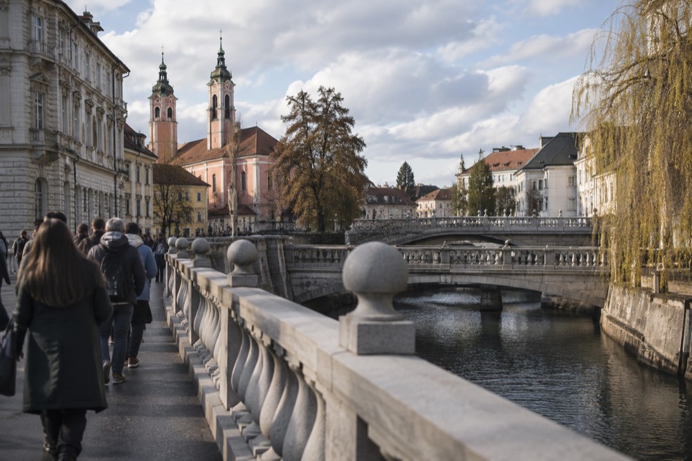 Stone riverbank with three bridges in one frame and church towers behind
