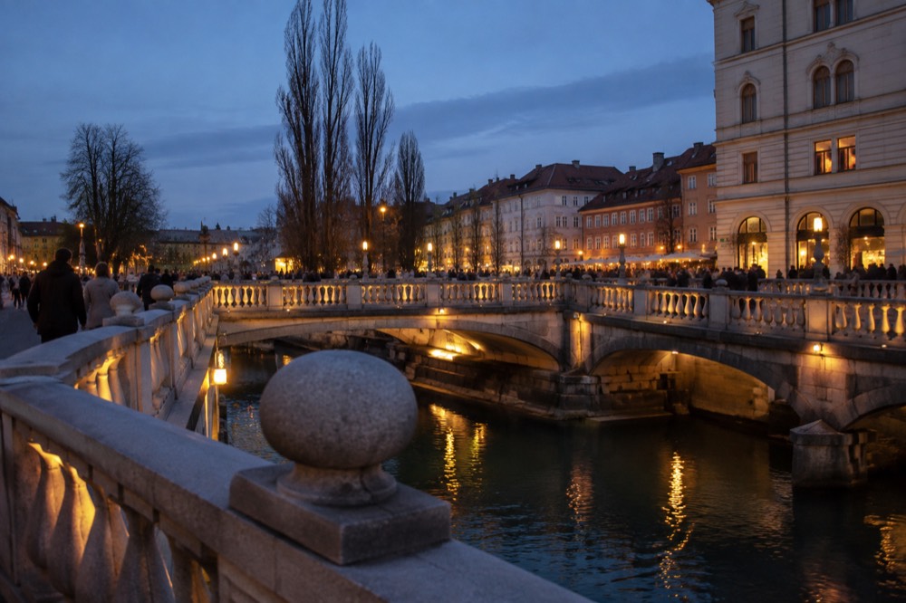 Evening view of three illuminated bridges with people crossing towards lit restaurant streets