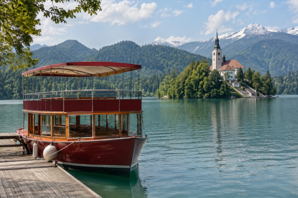 Red double-decker sightseeing boat moored on Lake Bled near the island