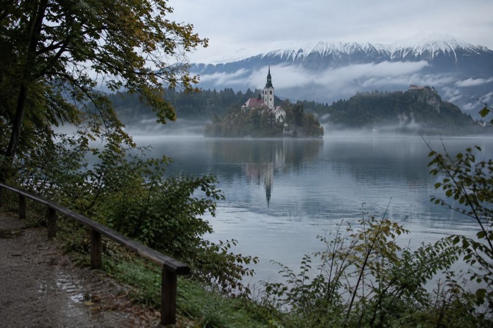 Morning mist over Lake Bled with the island silhouette and forested shore