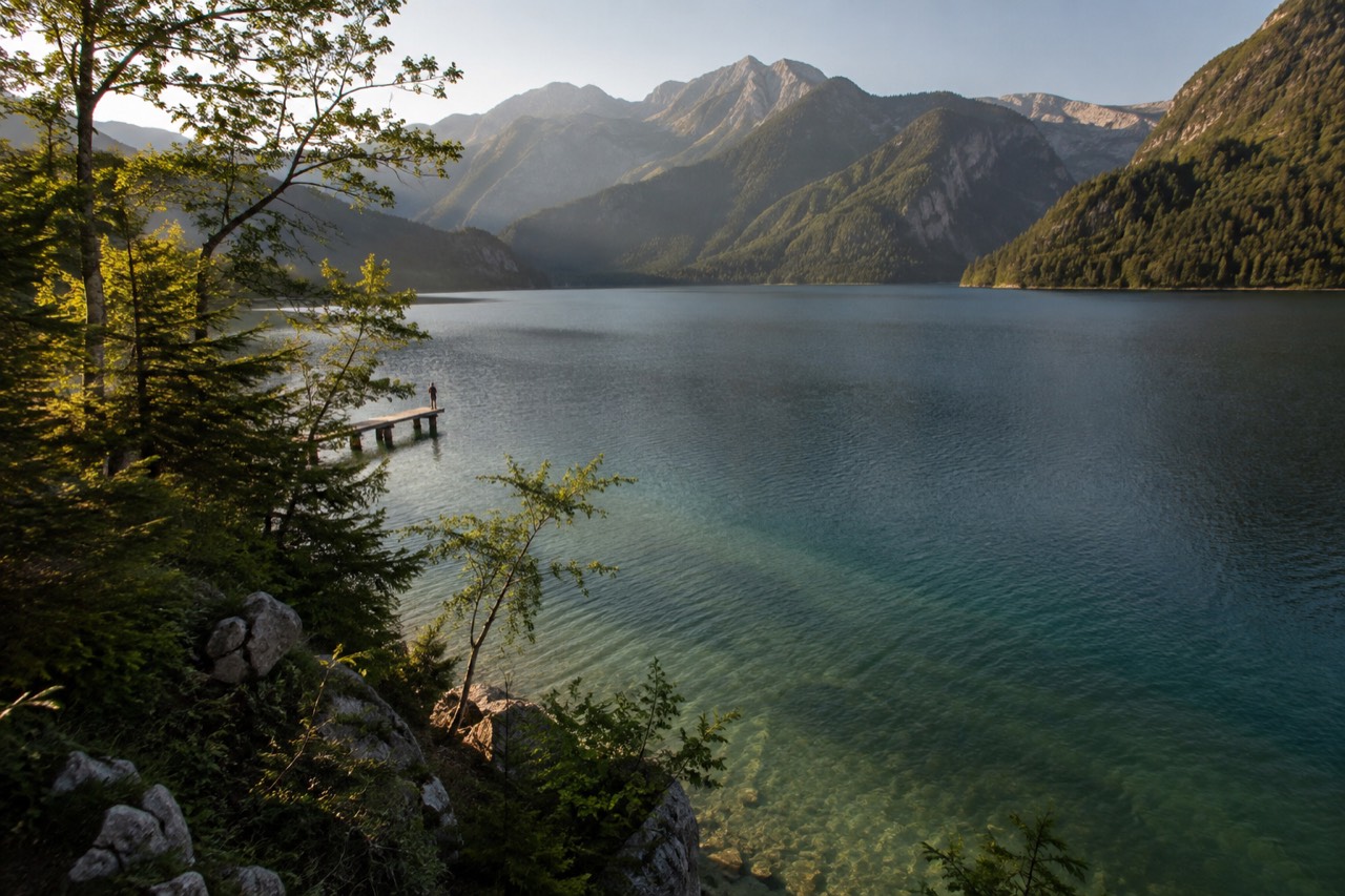 Turquoise Lake Bohinj framed by forested hills with the Julian Alps rising behind under a clear sky