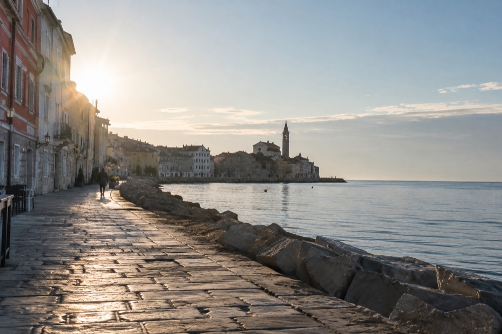 Empty stone promenade along the Piran sea wall in soft morning light