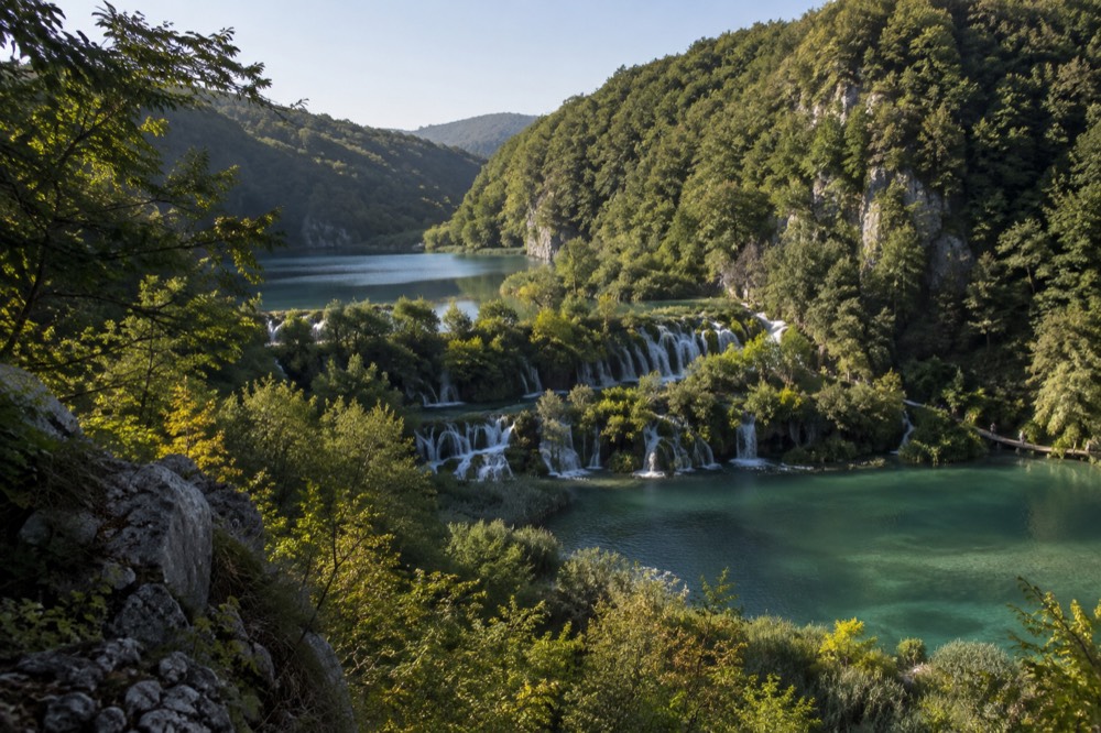 Wide view of stepped terraced lakes descending through dense green forest