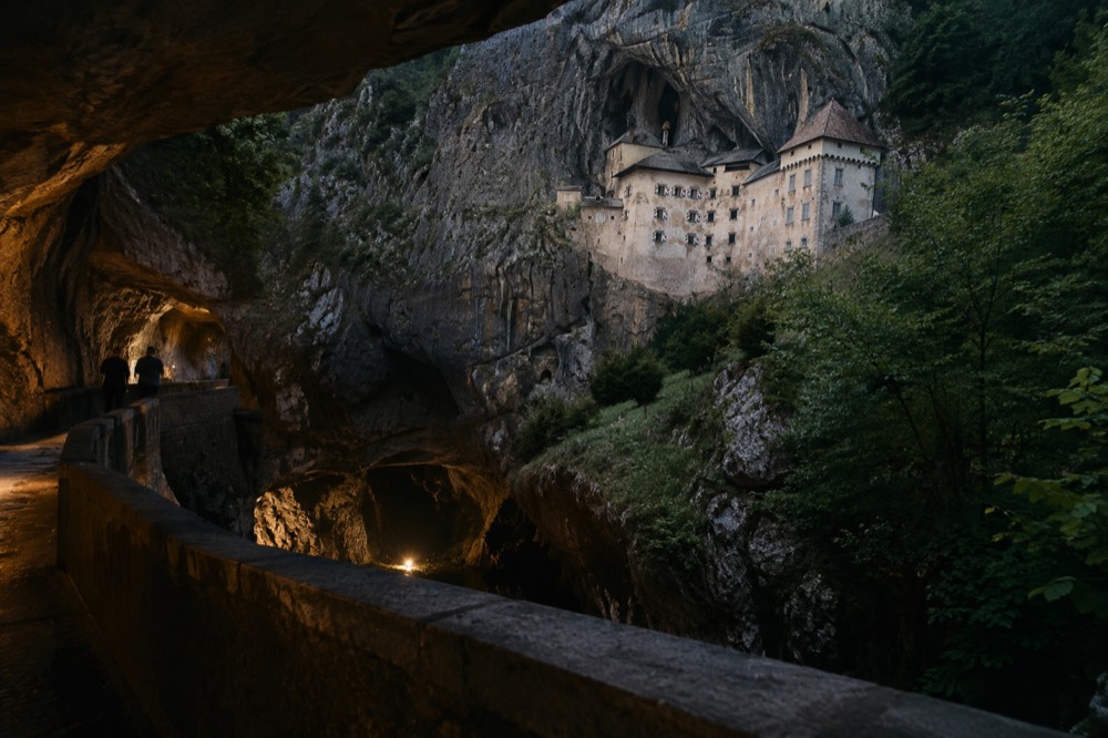 A stone bridge spanning a deep underground river canyon inside a lit cave