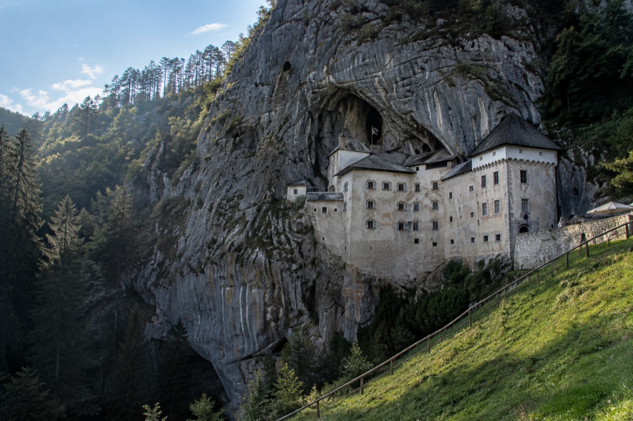 Predjama Castle built into the face of a limestone cliff above a green valley