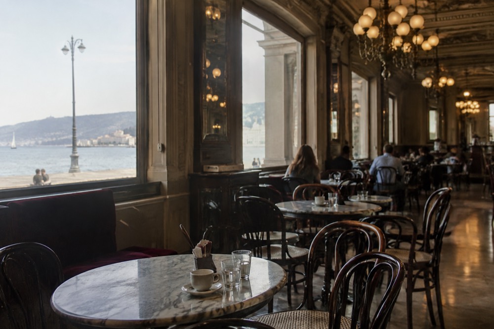 Historic cafe interior with marble tables and chandeliers