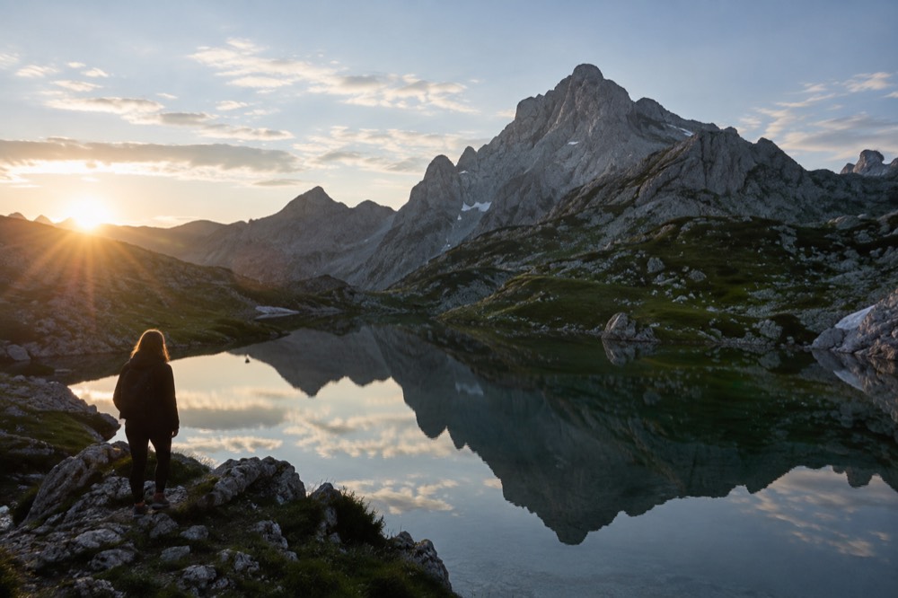 Steep mountain peak reflected in a still alpine lake at sunrise