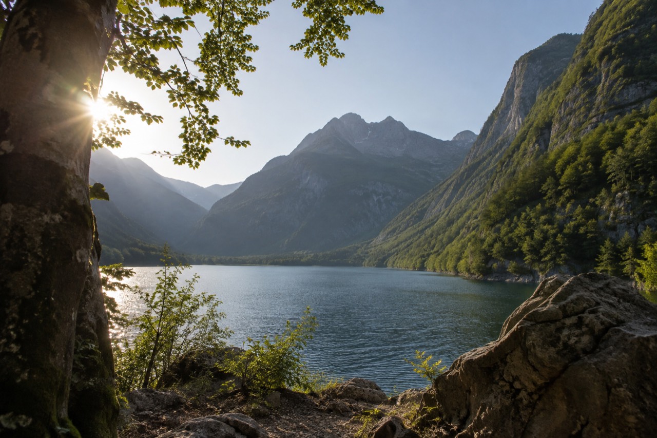 Mountain lake surrounded by steep green slopes under a clear sky in the Julian Alps
