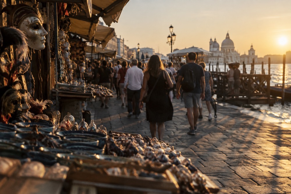 A busy Venetian street with crowds walking between souvenir stalls
