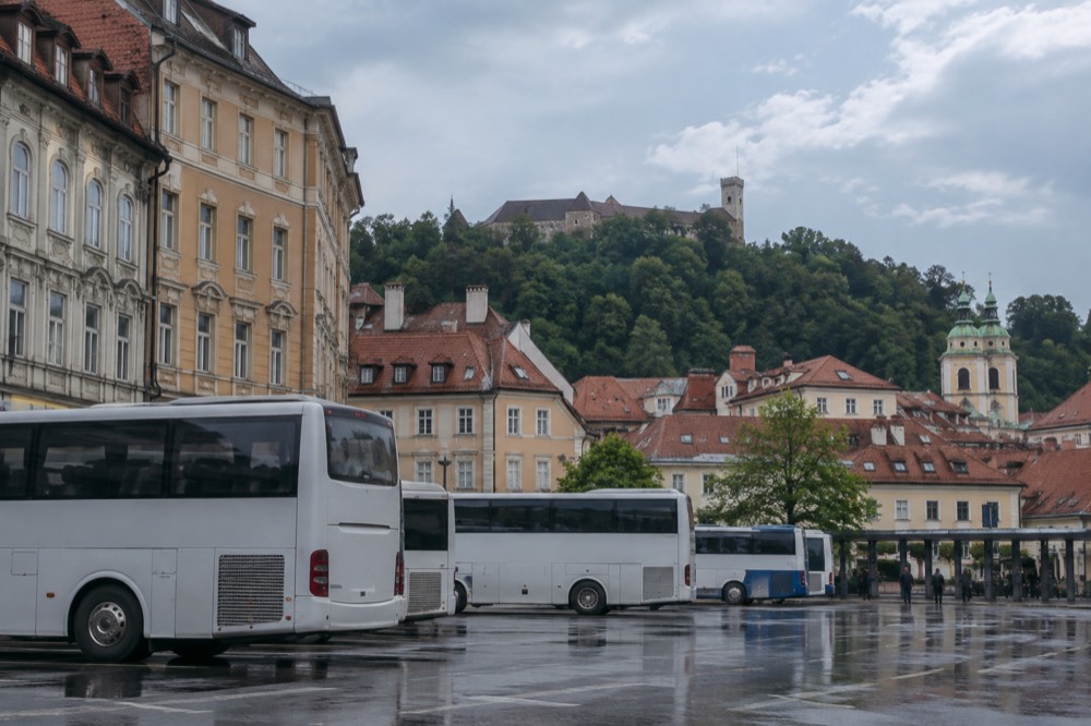 Buses parked at the Ljubljana bus station with the city's rooftops behind them
