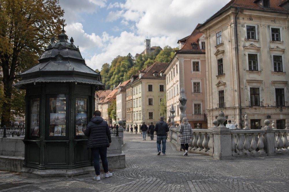 A tourist information kiosk beside a stone bridge in a city square