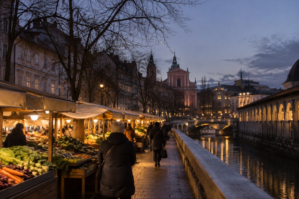 Wooden market stalls with glowing warm lights along a riverside street in the evening