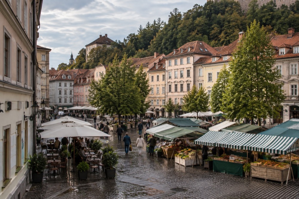 Open-air market stalls and café tables on a Ljubljana square in morning light