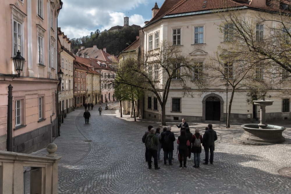 A guide speaking to a small group on a cobbled square in Ljubljana's Old Town