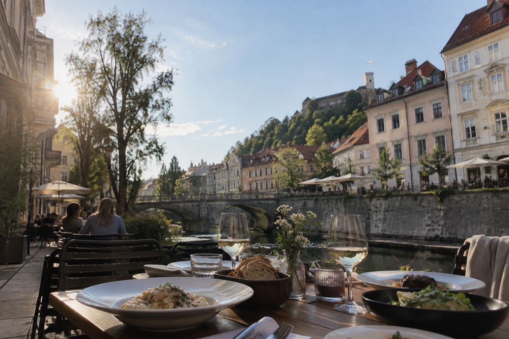 A table of Slovenian dishes and glasses of wine at an outdoor restaurant in central Ljubljana